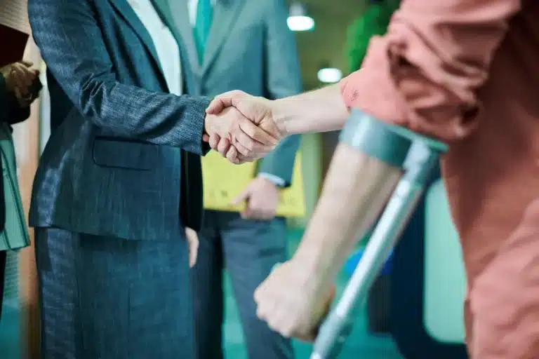 Injured person on crutches shaking hands with a legal professional