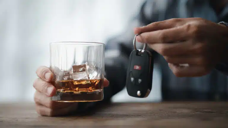 Man holding a glass of brandy, he is drinking brandy in a bar, drinking alcohol impairs driving ability and can damage health. The concept of drinking alcohol.