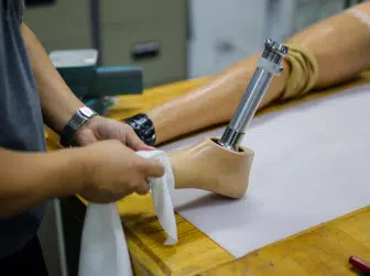 Technician assembling a prosthetic leg in a workshop setting.