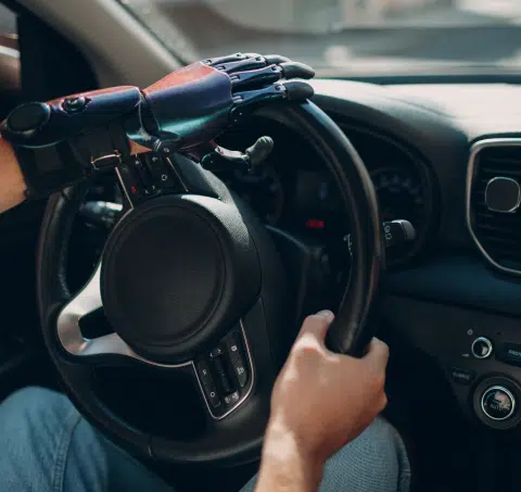 Young disabled man driver with artificial prosthetic hand driving vehicle car.