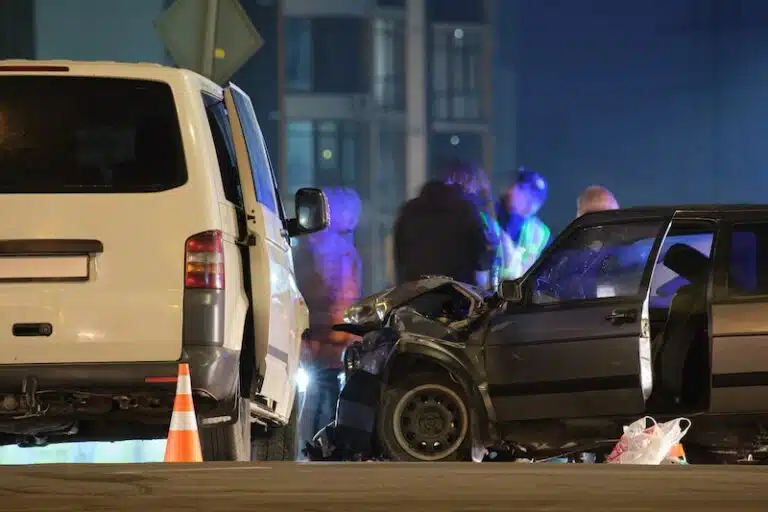 Cars crashed heavily in road accident after collision and silhouette of people on city street at night. Road safety and insurance concept