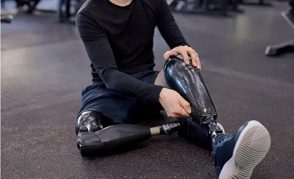Athlete with prosthetic legs adjusting gear during a gym workout.