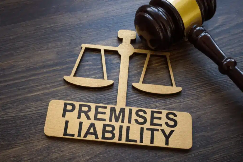 A wooden gavel rests beside a wooden cutout of the justice scales and a sign that reads "Premises Liability