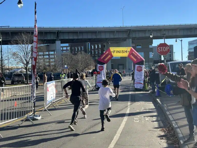 Participants running toward a finish line during a community outreach event