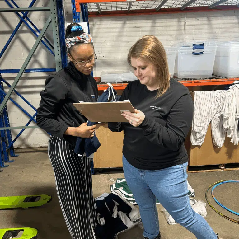 Volunteers checking an inventory checklist on a clipboard at a storage facility.