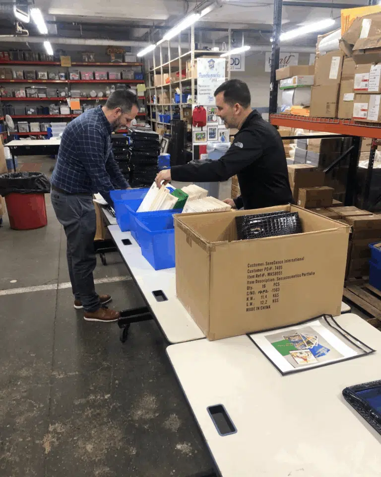 Two people packing supplies at a table during a community outreach activity