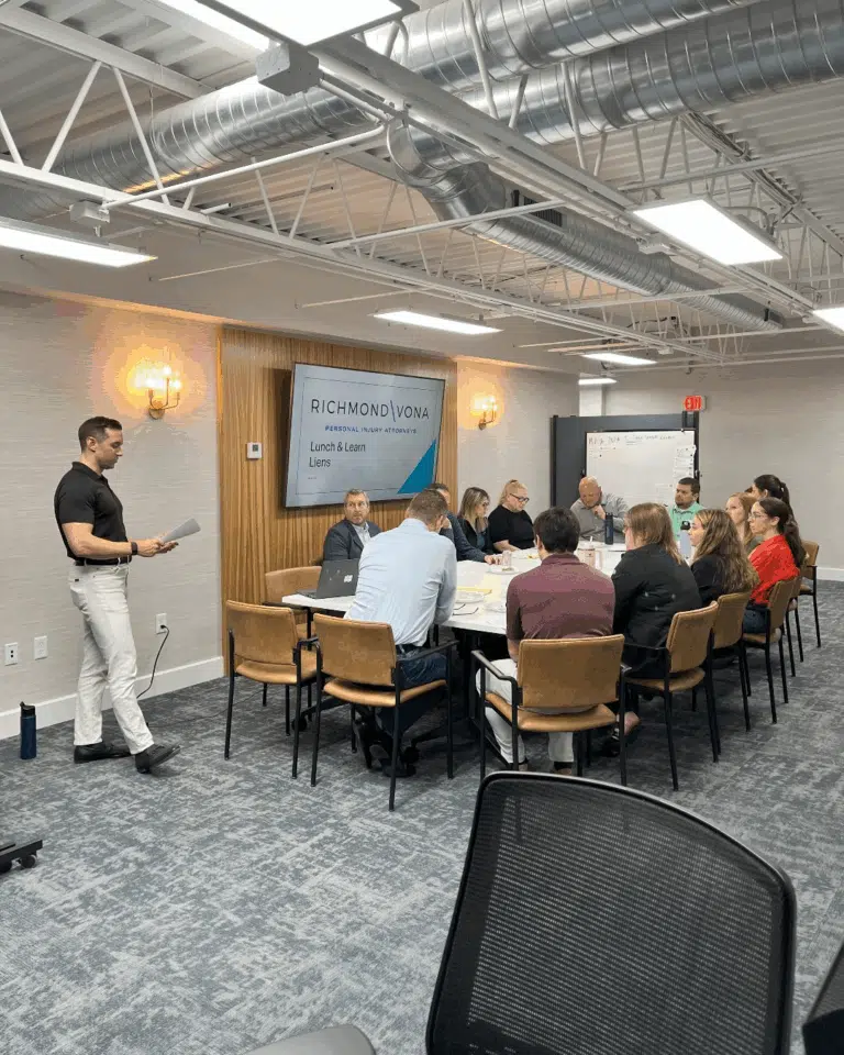 John Richmond presenting to a group in a conference room with the Richmond Vona logo on the screen.