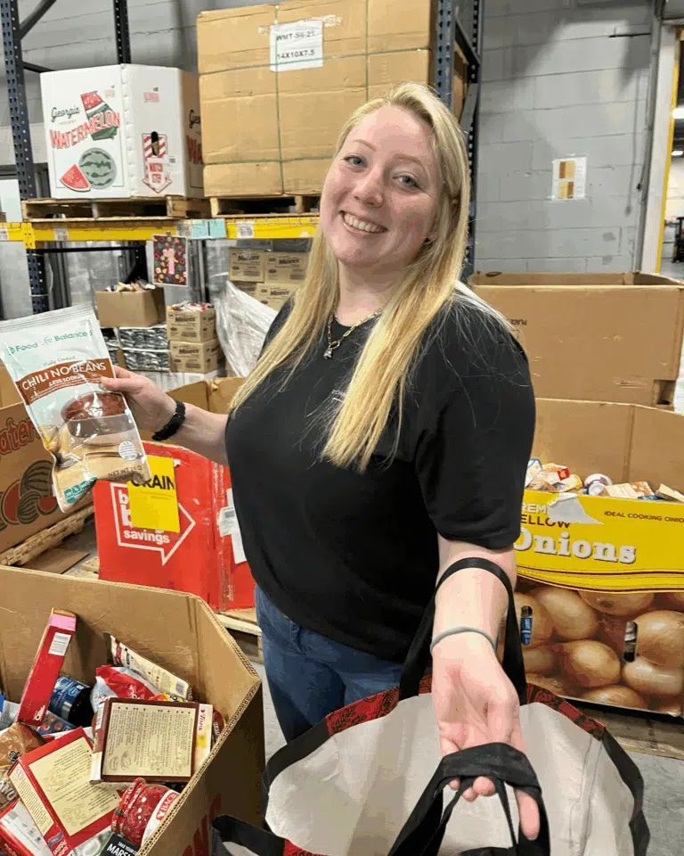 Woman standing beside donated food items during a community outreach activity
