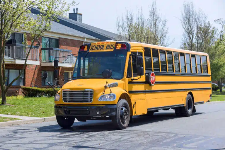 At suburban sleep area, yellow school bus is seen driving along street