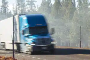 Semi truck driving down tree-lined highway