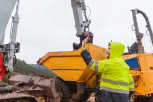 Man working on a construction site and giving instructions to his excavator shovel partner. person and work machinery