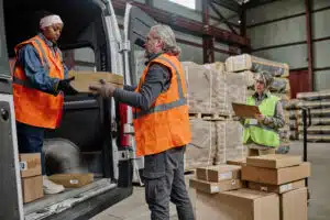 Warehouse workers loading cargo in truck with foreman controlling the working process in warehouse