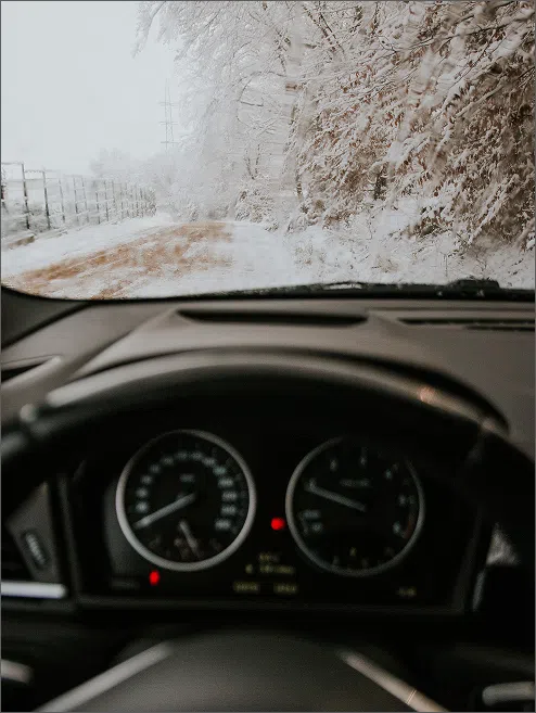 View from inside a car driving on a snow-covered road in winter.