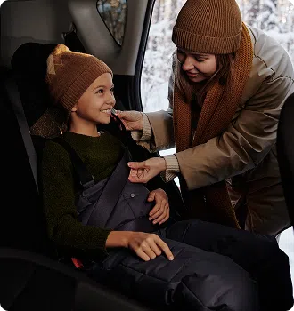 Woman fastening little girl on backseat of car