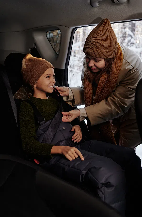 Woman fastening little girl on backseat of car