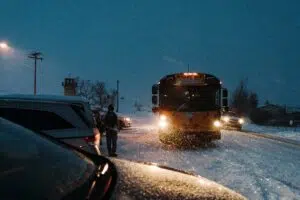 School bus driving on a snowy road at dusk