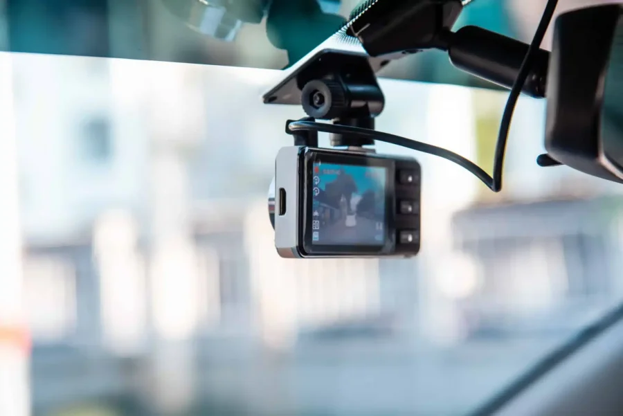 Close-up of a dashboard camera mounted on a windshield, recording traffic footage for vehicle safety and accident evidence