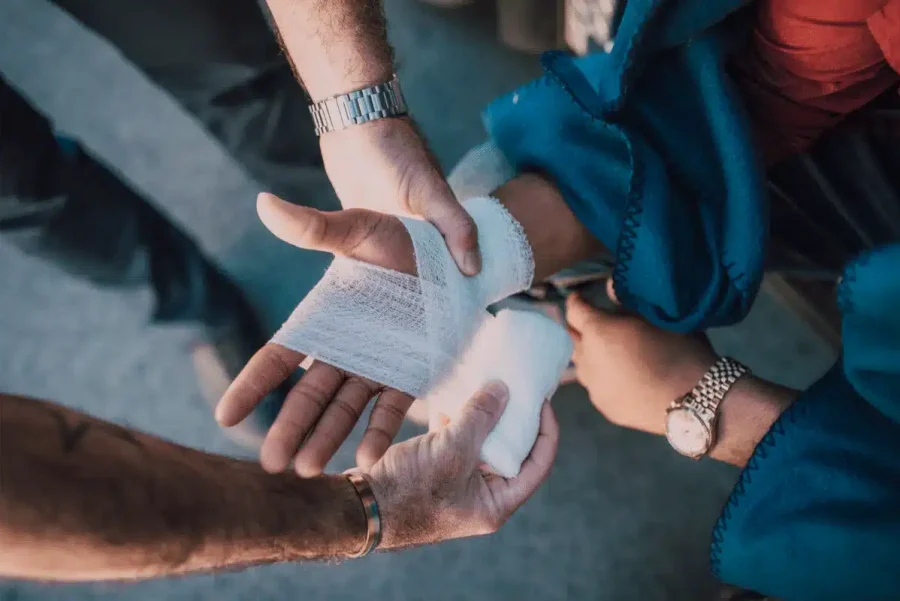 Close-up of a medical professional wrapping a patient's injured hand with gauze
