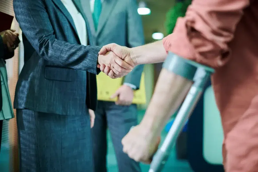 Injured person on crutches shaking hands with a legal professional