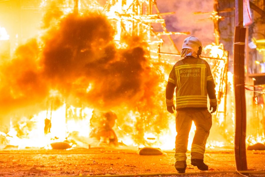 fireman trying to control a fire in a street during a night.
